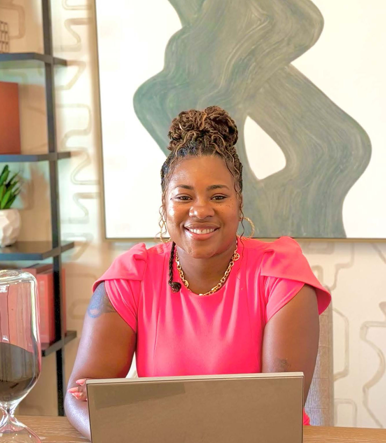 Kenisha Braswell, Licensed Clinical Social Worker, smiling while seated at a desk with a laptop, symbolizing warmth and approachability for her counseling practice.