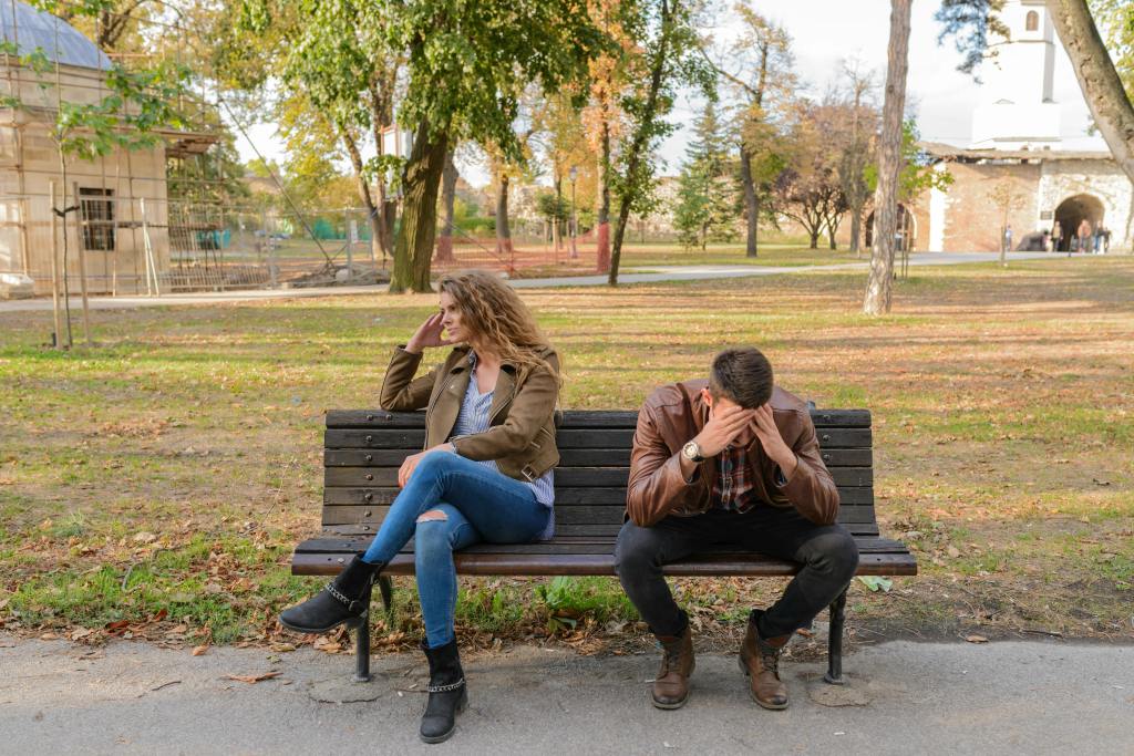 Couple sitting apart on a park bench symbolizing distance, reflection, and healing after relationship loss.